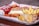 A tray holds a selection of fast food items including a can of Coca-Cola, a basket of french fries, a sandwich with a waffle-like texture on the bread, and several breaded chicken nuggets.