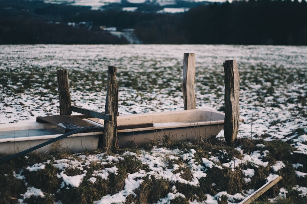 brown wooden boat on snow covered ground near body of water during daytime