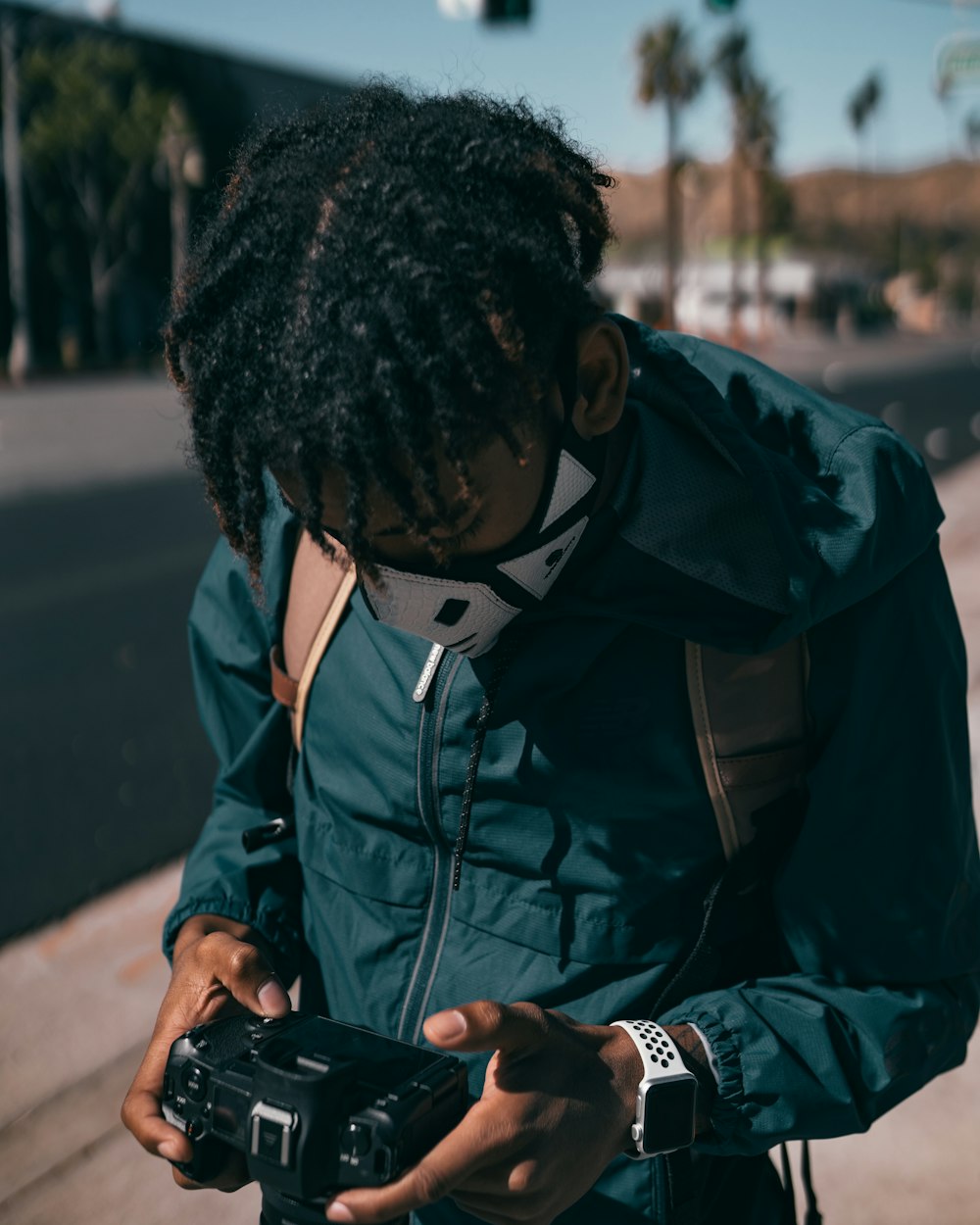 man in blue jacket holding black smartphone