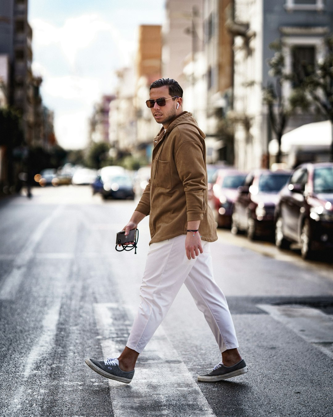 man in brown coat and white pants sitting on road during daytime
