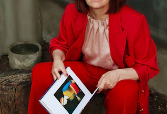 a woman in a red suit is holding a book