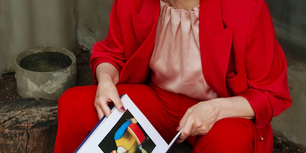 a woman in a red suit is holding a book