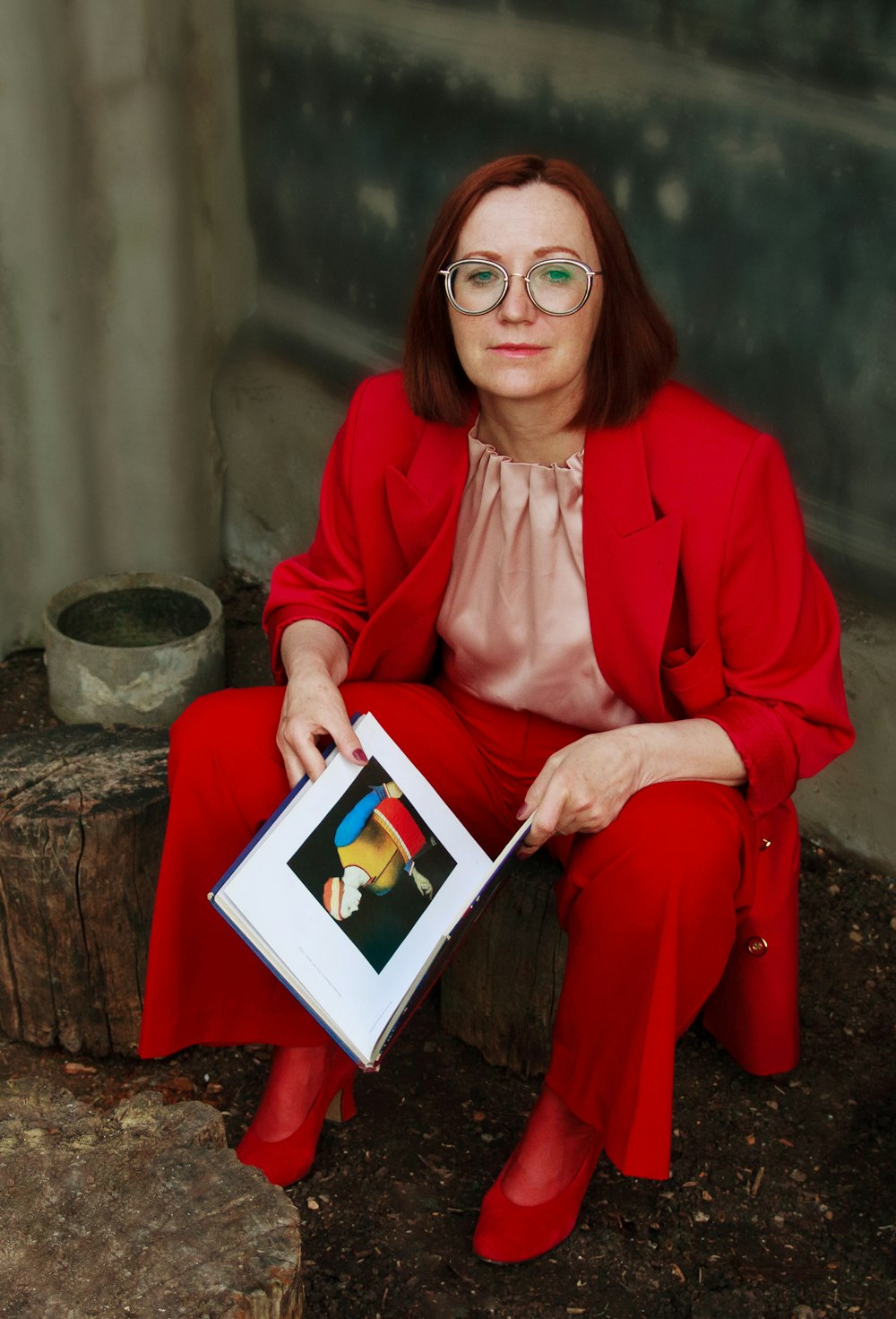 a woman in a red suit is holding a book