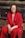 a woman in a red suit sitting on a tree stump