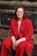 a woman in a red suit sitting on a tree stump