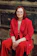 a woman in a red suit sitting on a tree stump