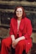 a woman in a red suit sitting on a tree stump