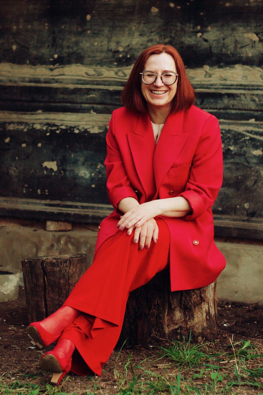 Femme en blazer rouge et jupe noire assise sur des escaliers en béton brun