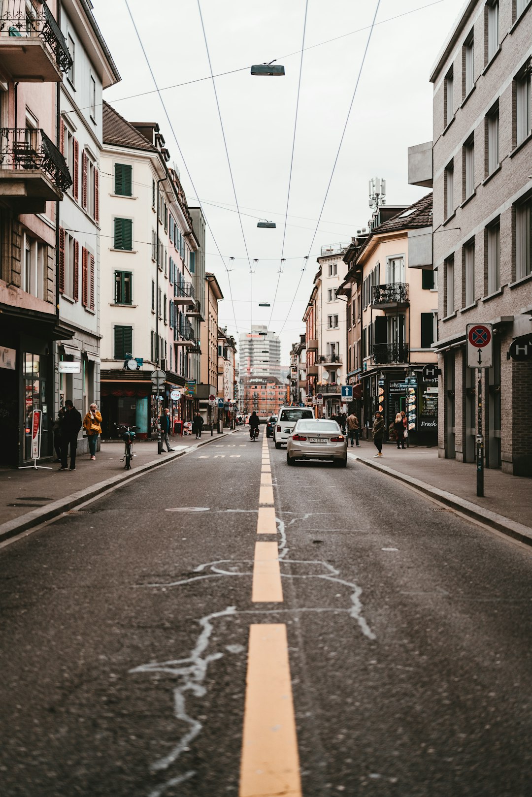 cars parked on side of the road in between buildings during daytime