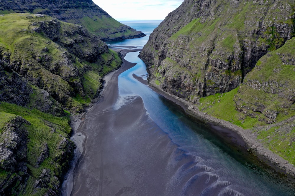 river between green grass covered mountains during daytime