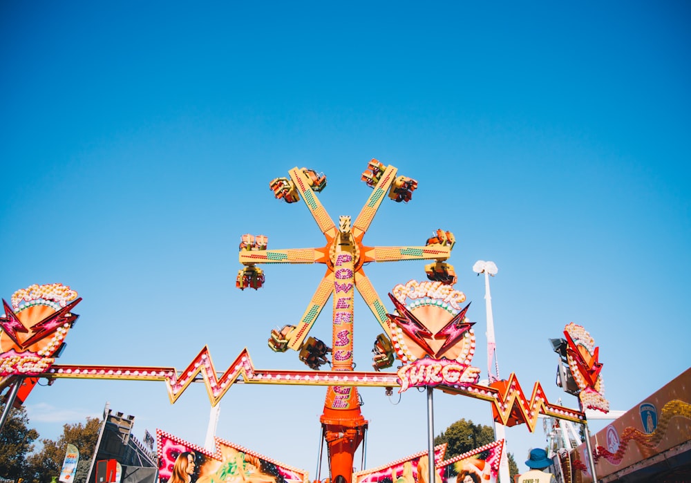 red and yellow metal amusement park ride under blue sky during daytime