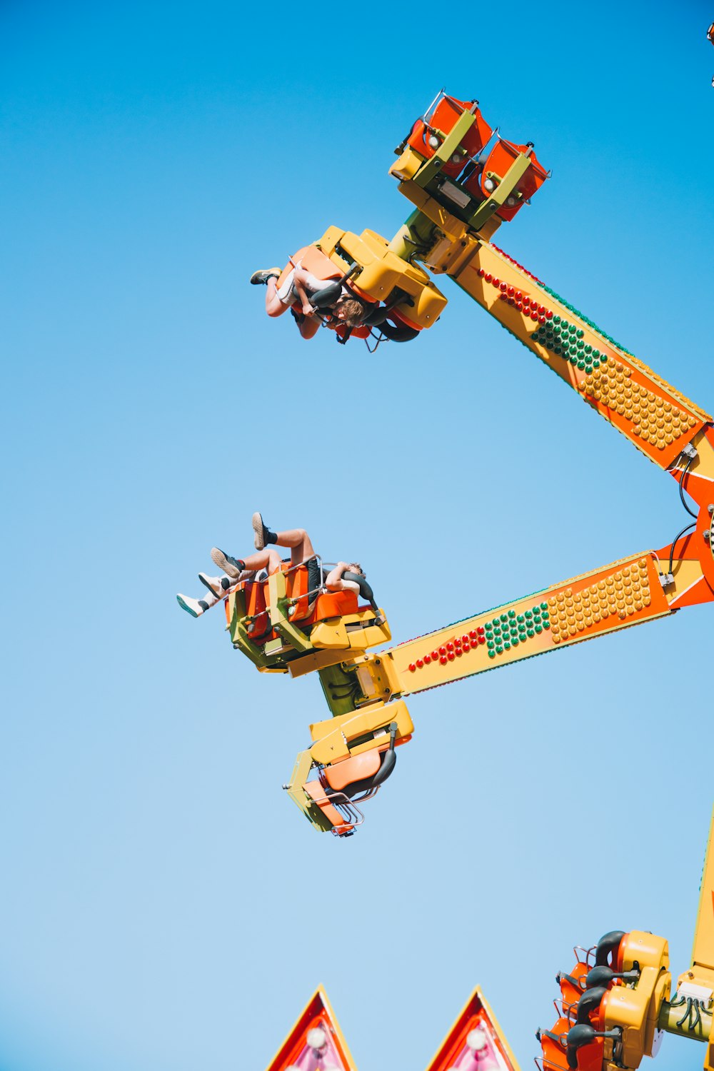 people riding on yellow and red roller coaster during daytime