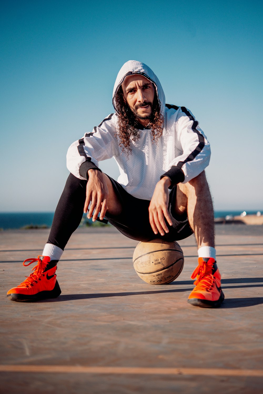 woman in blue and white jacket and black pants sitting on basketball hoop