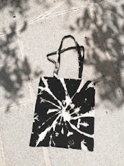 Artistic black and white photo of a tote bag with a subtle soundwave pattern.