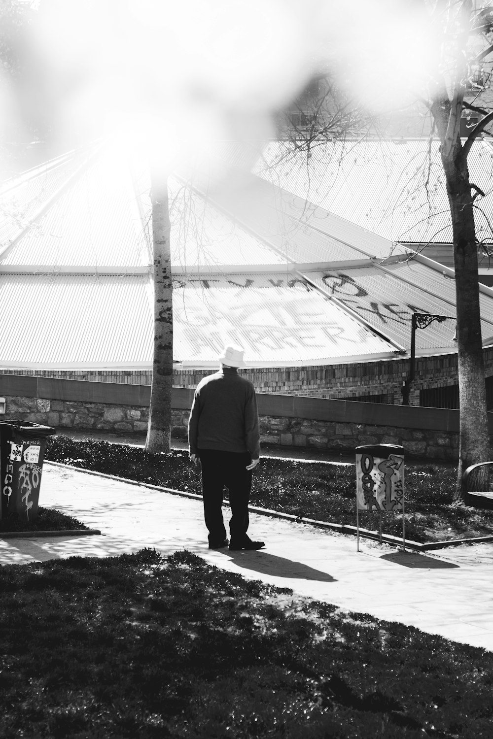 grayscale photo of man and woman walking on sidewalk