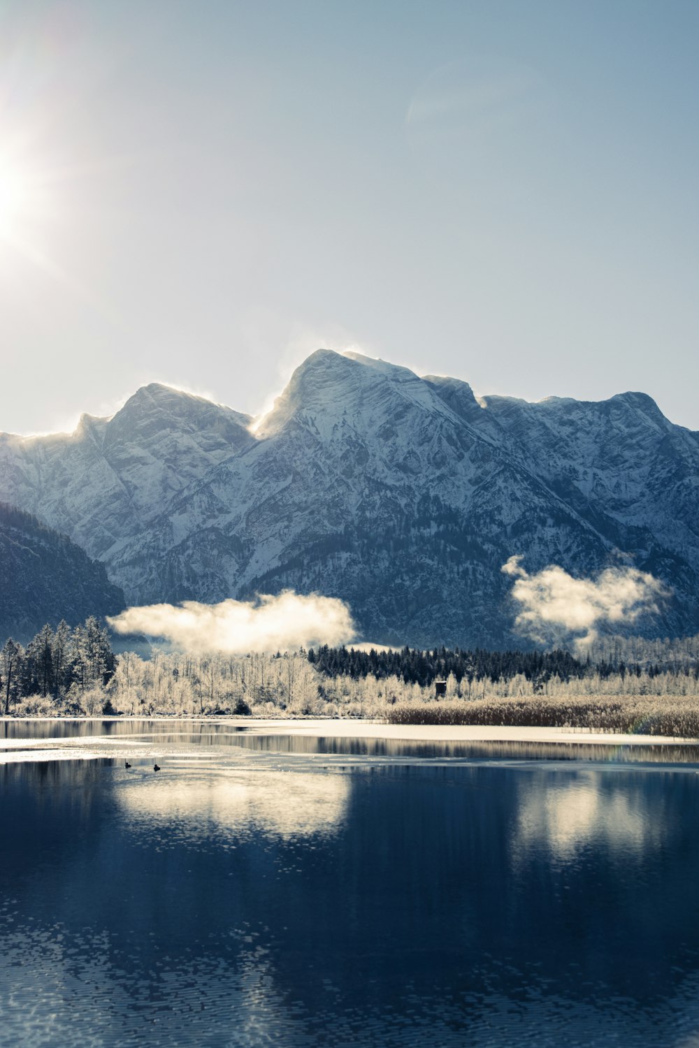 snow covered mountain near body of water during daytime