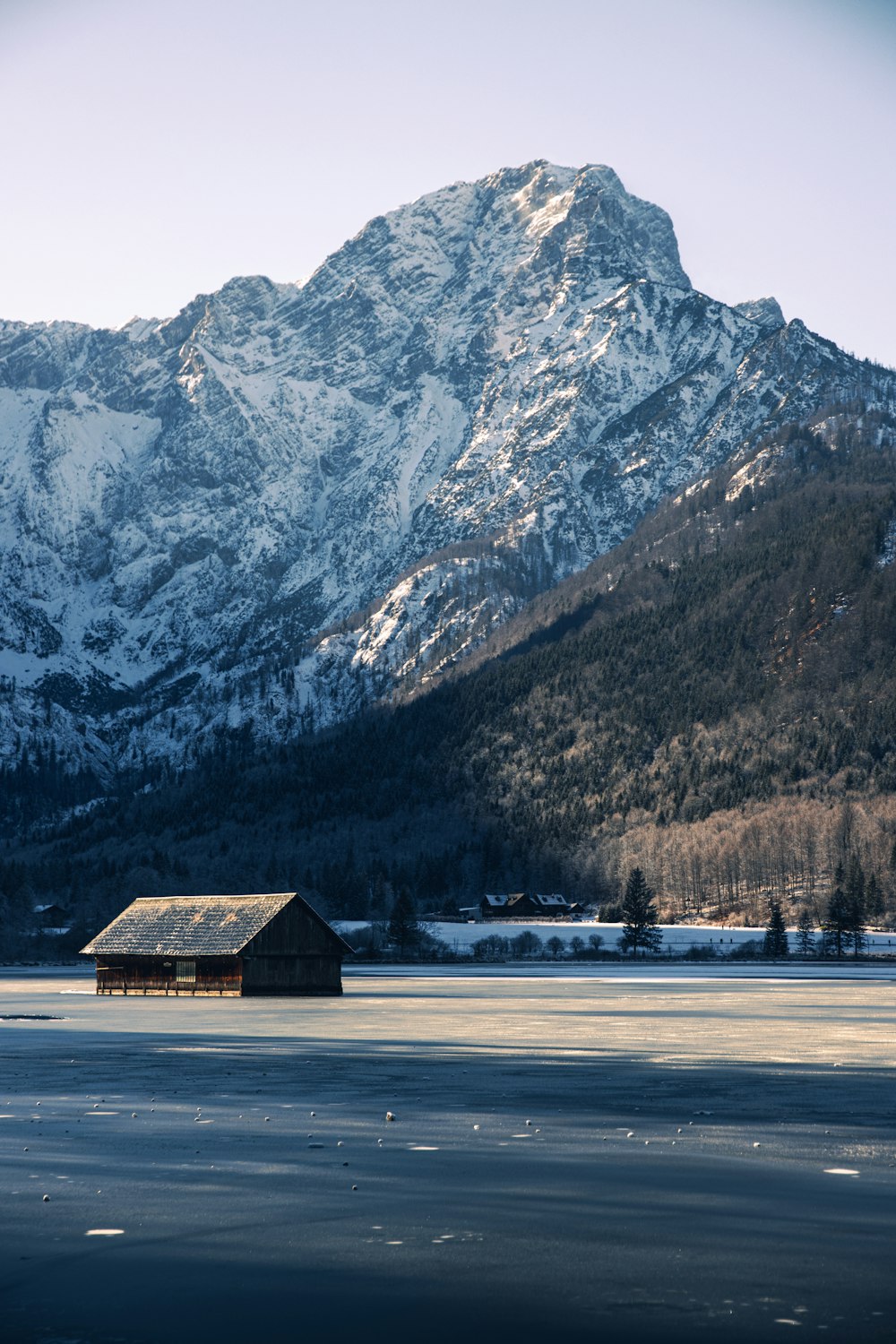 brown wooden house near snow covered mountain during daytime