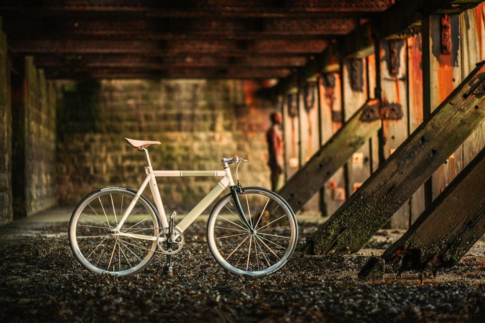 white city bike parked beside brown wooden fence during daytime