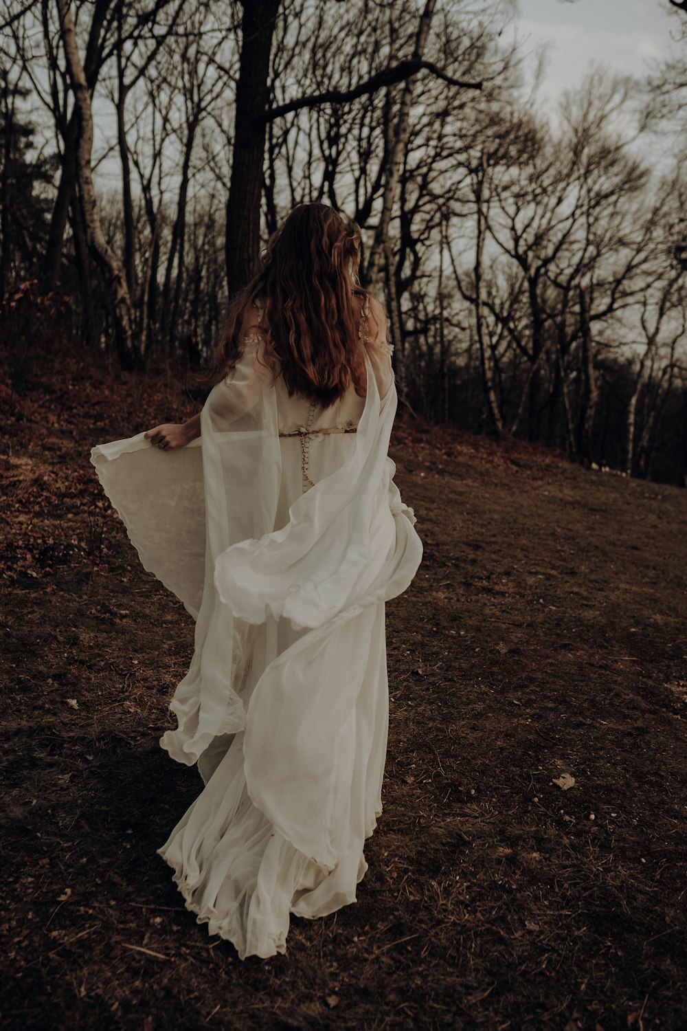 茶色の土の上に立つ白いドレスを着た女性