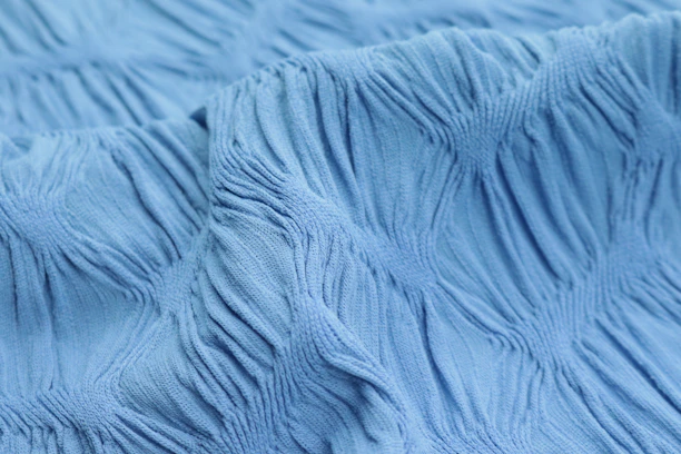 Close-up of a luxurious Pacific Blue swimsuit fabric texture with ocean reflections.