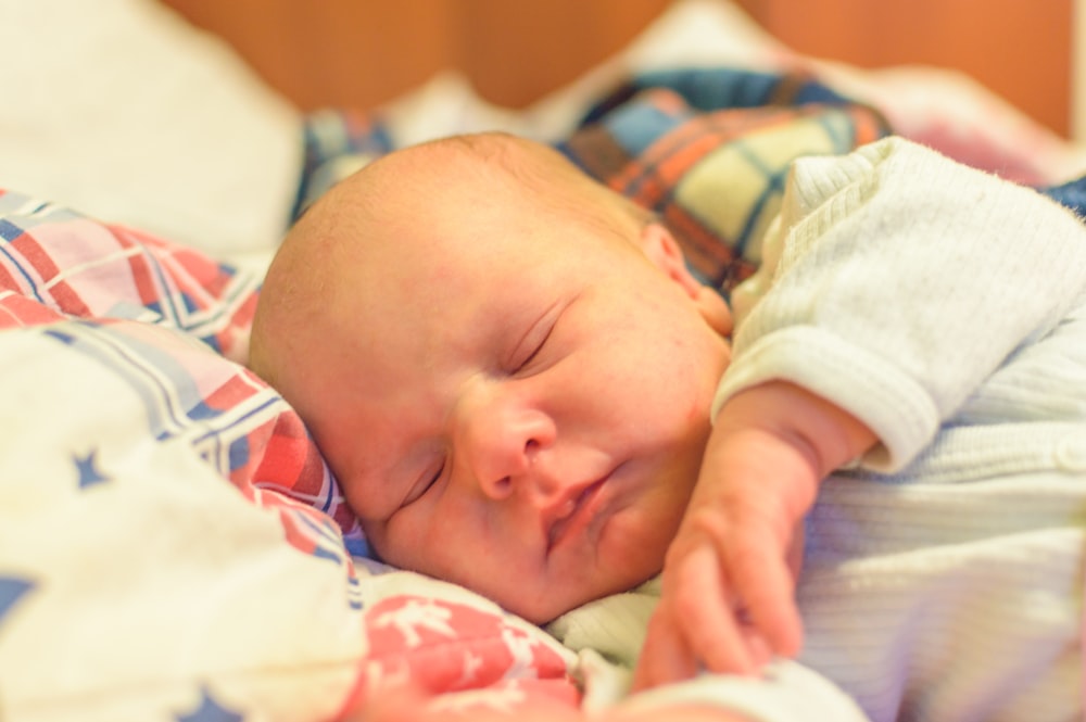 침대에 누워 있는 흰색과 파란색 옷을 입은 아기