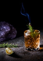 clear drinking glass with yellow liquid and green leaves