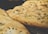 Golden-brown flatbreads with a textured surface, topped with an even distribution of chopped herbs. The breads have a crispy and slightly uneven crust, indicating a freshly baked texture.