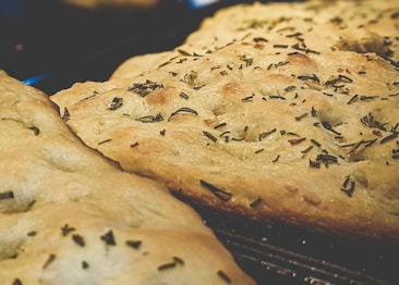 Golden-brown flatbreads with a textured surface, topped with an even distribution of chopped herbs. The breads have a crispy and slightly uneven crust, indicating a freshly baked texture.