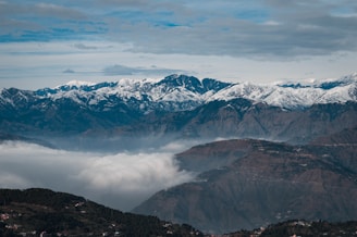 snow covered mountains under cloudy sky during daytime