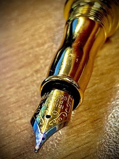 Close-up of a vintage pen with intricate mother-of-pearl inlay resting on a clean white surface.
