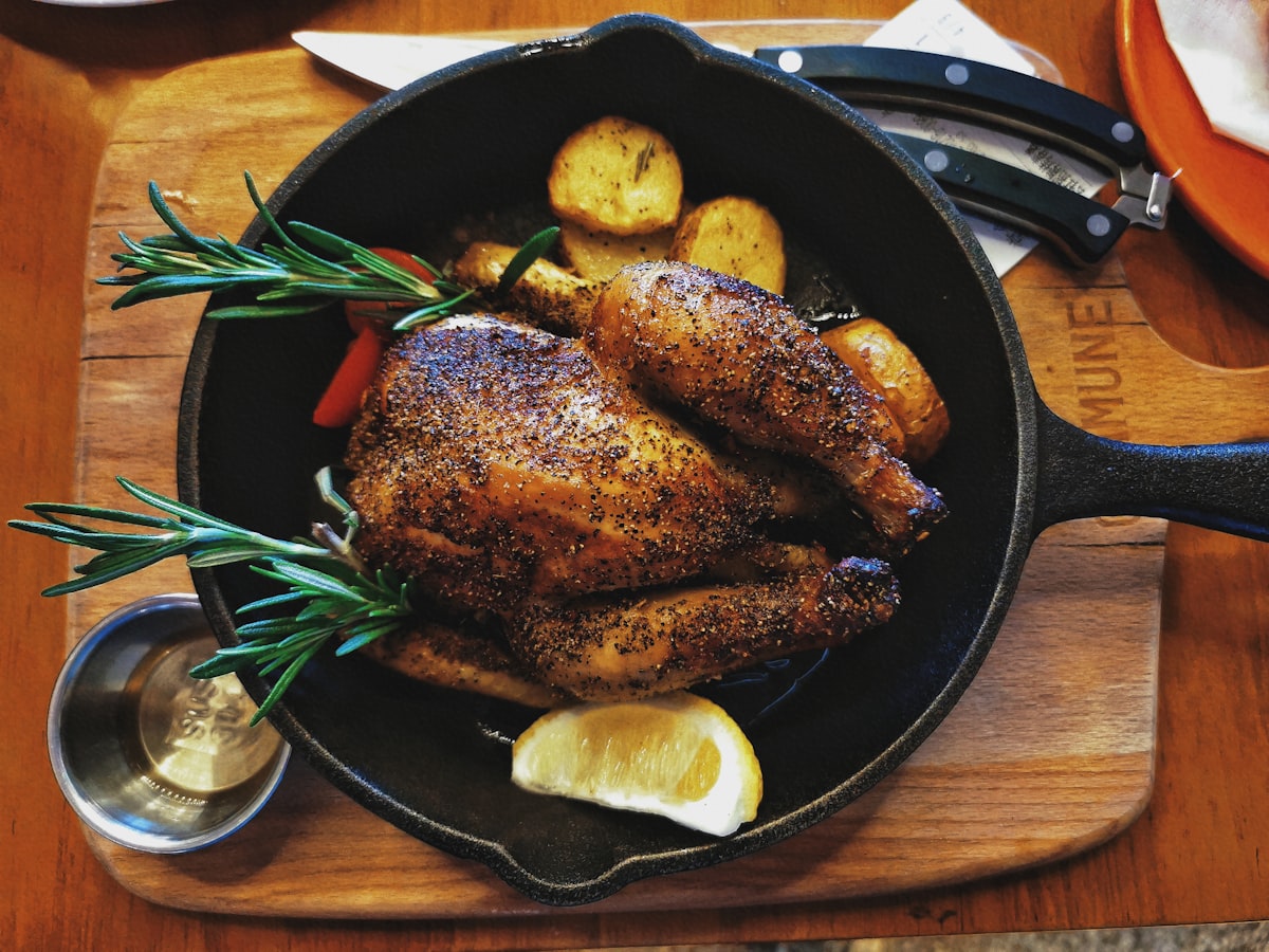 Roasted chicken quarters served on black plate with lime and green sauce