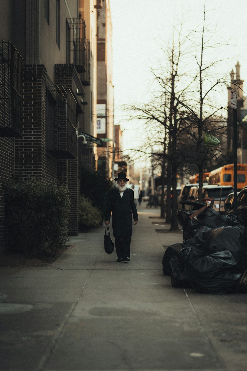 man in black coat walking on sidewalk during daytime
