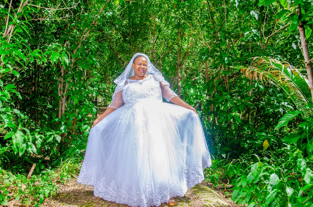 woman in white wedding dress standing on green grass field during daytime