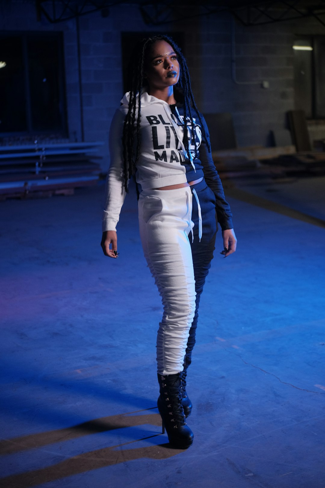woman in black leather jacket and white pants standing on blue floor