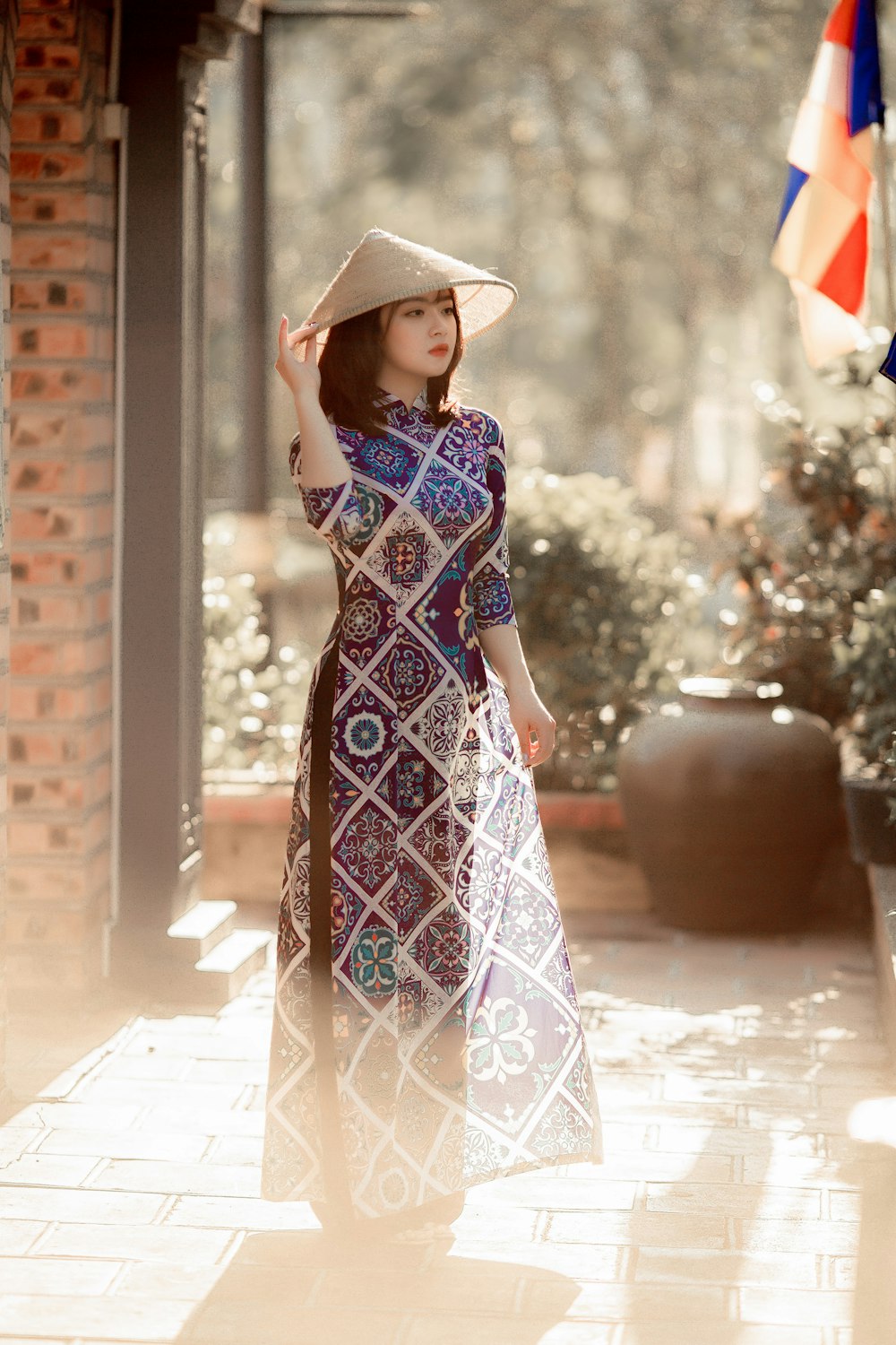 woman in blue and white floral dress wearing brown hat standing on gray concrete floor during