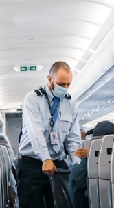 man in blue dress shirt standing in airplane