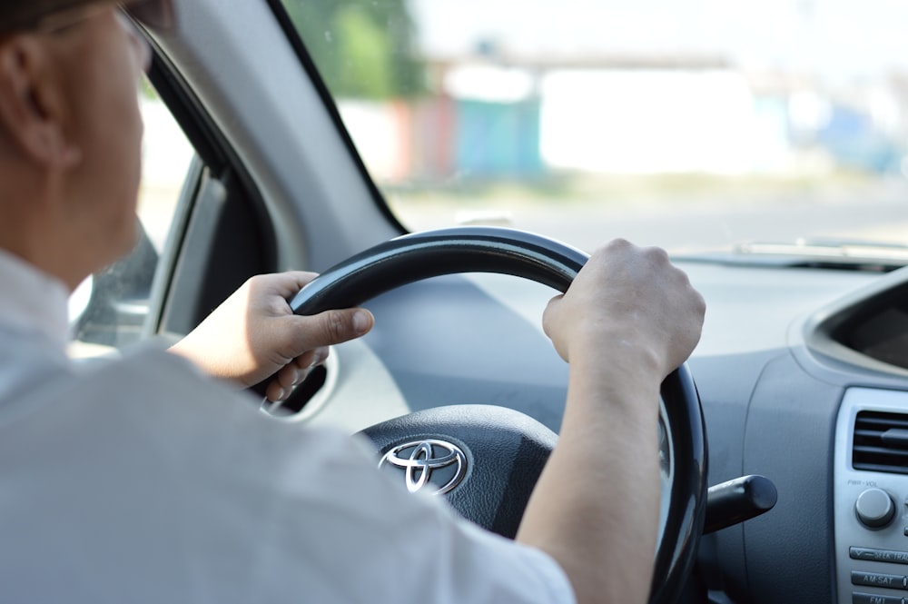 白い長袖シャツを着た人が車を運転している