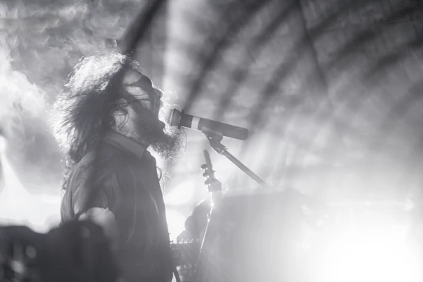 Close-up of the artist passionately performing with dramatic black and neon effects.