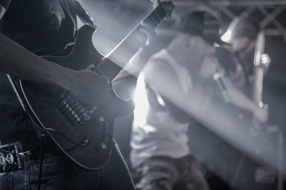 uomo che suona la chitarra elettrica nella fotografia in scala di grigi