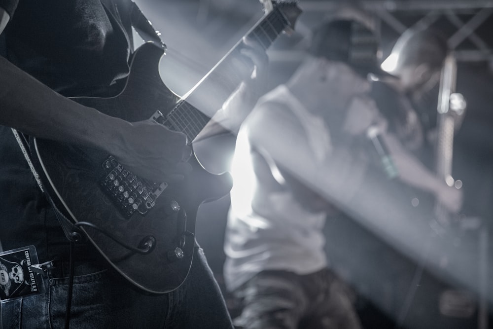 homem que joga guitarra elétrica na fotografia em tons de cinza