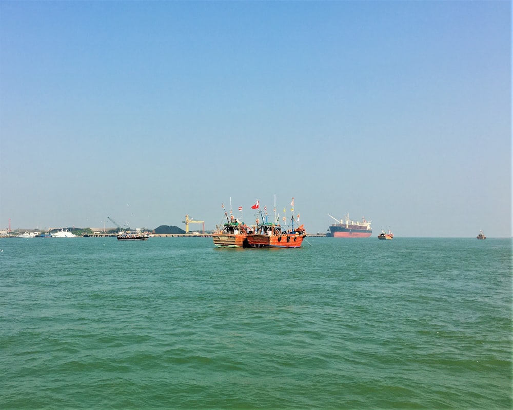 red and white boat on sea under blue sky during daytime