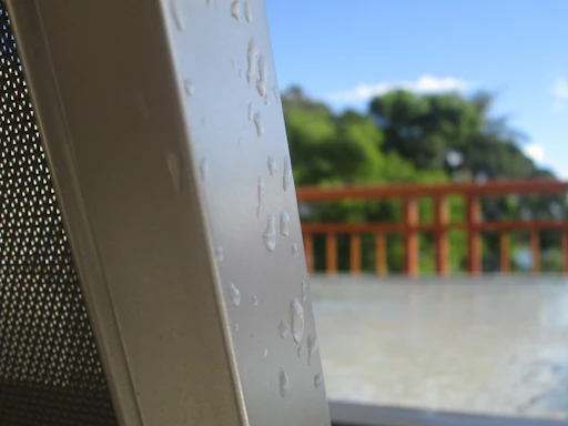A close-up of water droplets sliding off a waterproof surface on a building exterior.