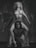 A black and white photo features a woman with curly hair and a bikini standing on the shoulders of a crouching man. The composition is dramatic and artistic, with a focus on their expressions and poses.