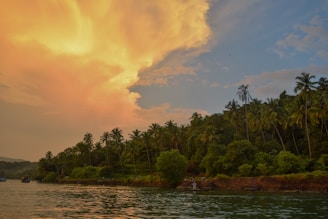 A serene coastal view of Kaimana with traditional boats and lush green hills under a golden sunset.