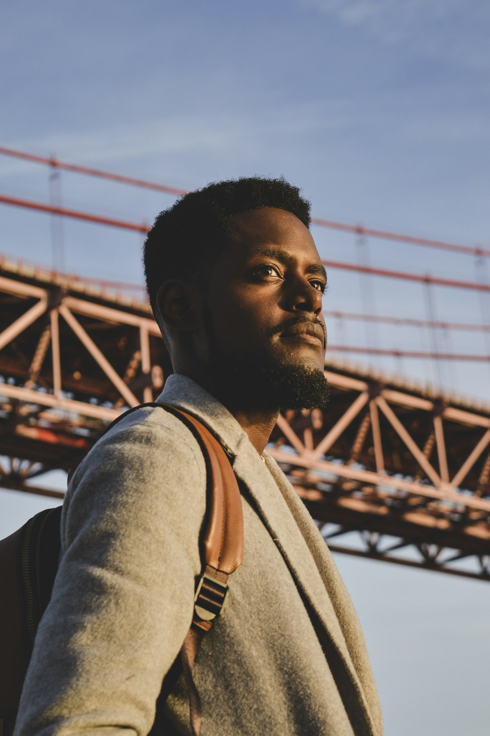 homme en chemise grise debout près du pont pendant la journée