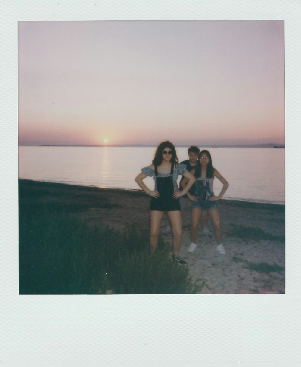 3 women sitting on green grass field near body of water during daytime