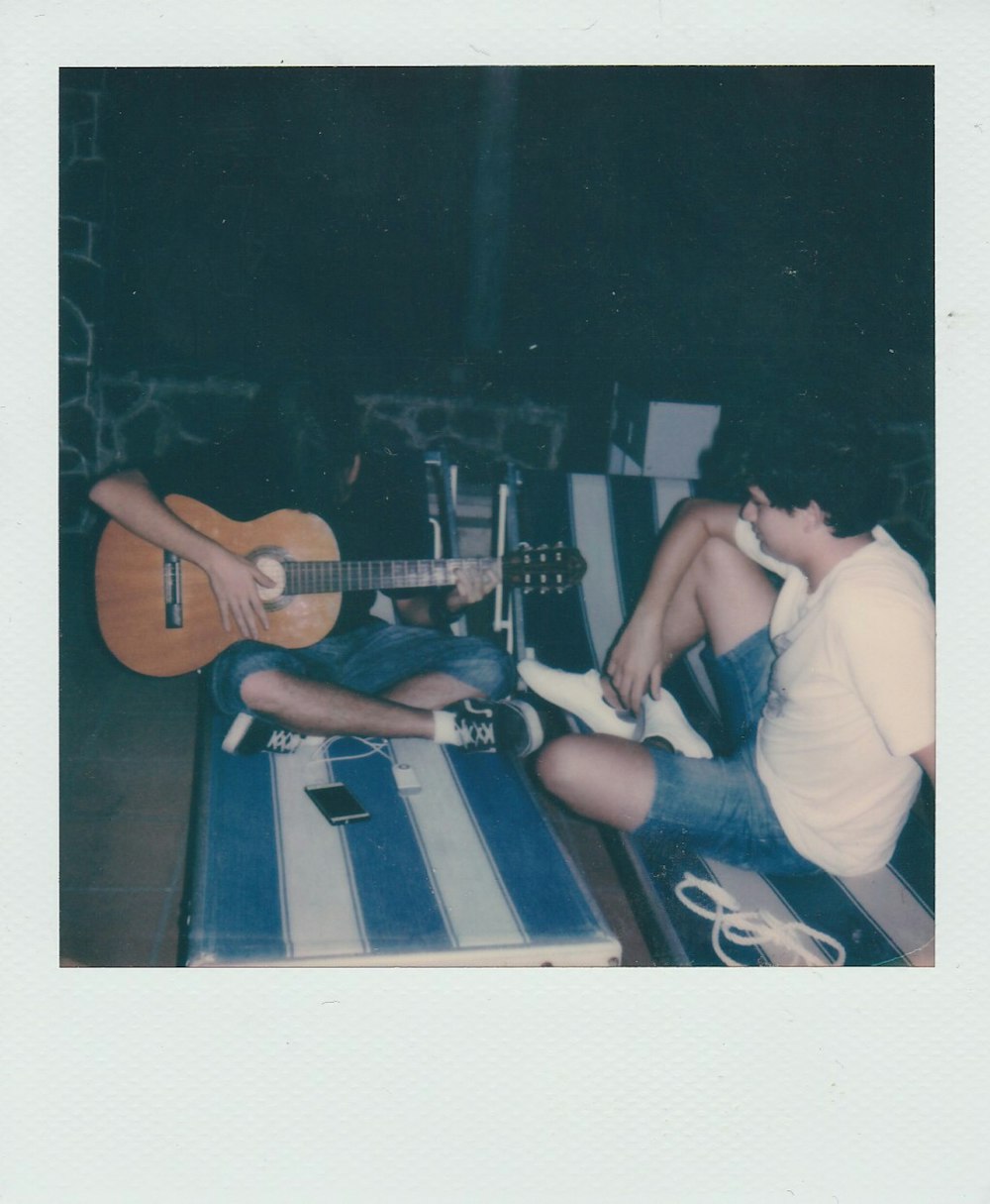 man in white t-shirt playing acoustic guitar