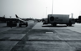 An airport tarmac with several parked aircraft from SpiceJet and a catering truck labeled 'LSG Sky Chefs'. The scene is busy with airport personnel and various ground service equipment visible. The image appears to be taken on a clear day with a control tower in the background.