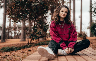 woman in red and black zip up jacket sitting on brown wooden bench