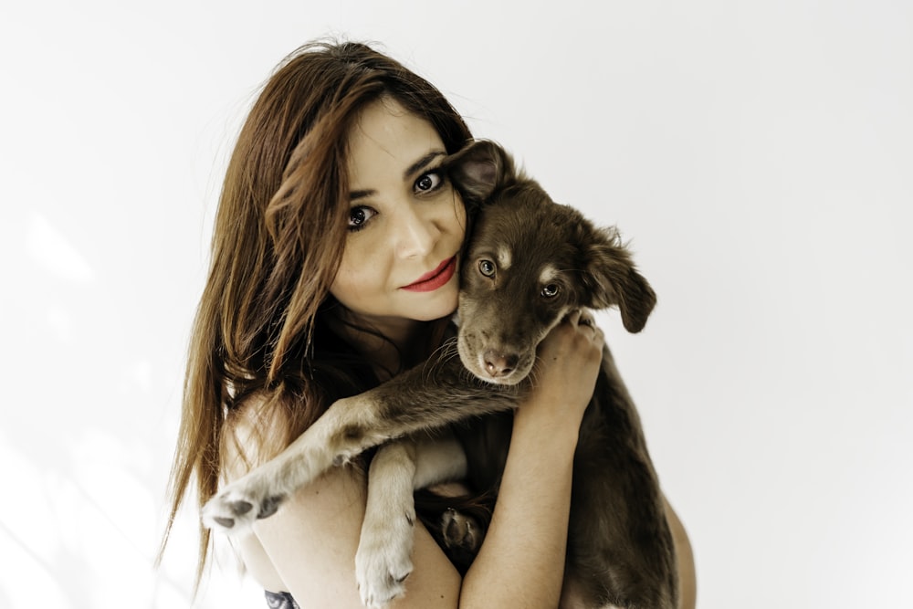 woman in black tank top hugging brown short coated dog